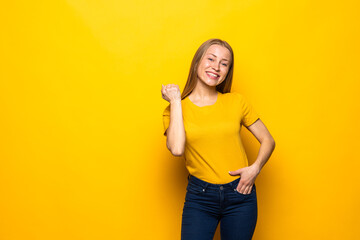 Young woman celebrating a victory over isolated yellow background