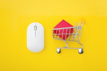 Computer mouse with red box in shopping cart on yellow background