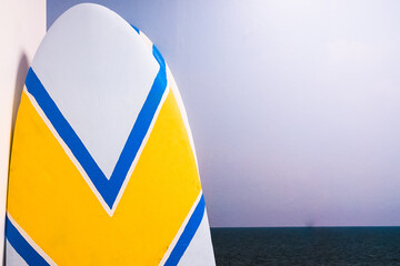 A simple surfboard resting inside a room, forgotten without use in the storage room.