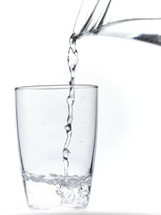 Glass of water being filled. Close up pouring clear water in transparent drinking glass over white background