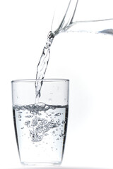 Glass of water being filled. Close up pouring clear water in transparent drinking glass over white background