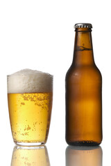 Brown beer bottle and a glass of beer in a white background. Beer brown bottle with drops and a full glass of beer isolated in white background