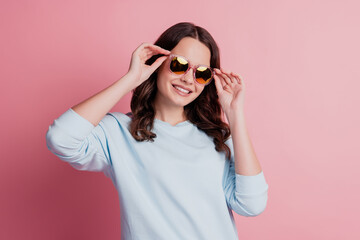 Charming lovely lady fashion model posing in sunglass on pink background