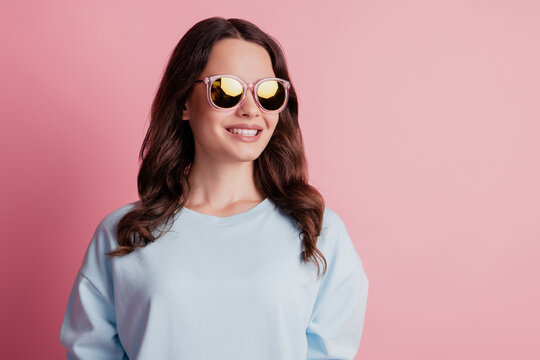 Photo of charming tender girl posing look empty space dream in sunglass on pink background