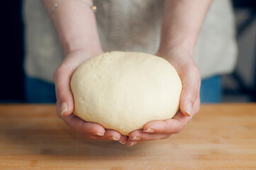 Woman holds bread dough in her hands