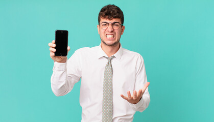business with a smartphone looking angry, annoyed and frustrated screaming wtf or what’s wrong...