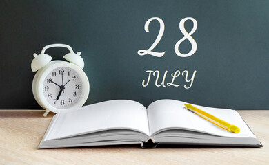 july 28. 28-th day of the month, calendar date.A white alarm clock, an open notebook with blank pages, and a yellow pencil lie on the table.Summer month, day of the year concept