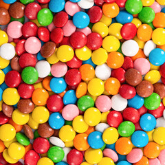 Fototapeta na wymiar Colorful small chocolate dragee. Multicolored button-shaped candies as background.