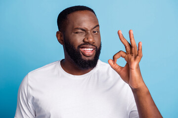 Photo of african businessman show okey sign blink eye on blue background