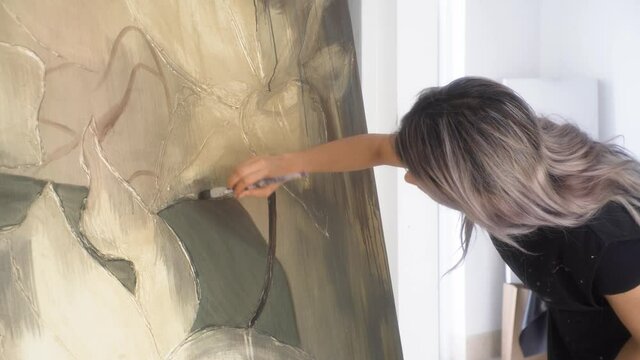 Latina female artist working on big painting project with brush