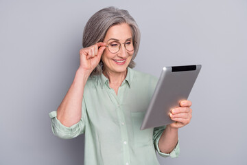 Photo of happy smiling lovely charming mature businesswoman promoter work in tablet isolated on grey color background