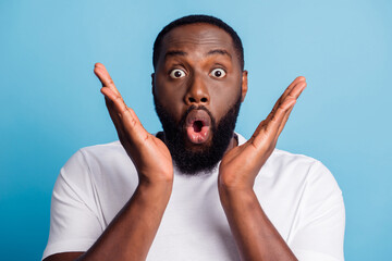 Photo of shocked funky young man open mouth palms face wear white t-shirt over blue background