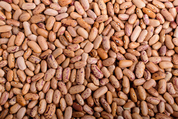 Natural background of many fresh organic red beans in a plastic box in warm light, top view or flat lay of organic vegan food photographed with soft focus