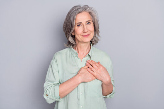 Photo Of Happy Smiling Dreamy Lovely Granny Hold Hands Chest Thankful Grateful Isolated On Grey Color Background