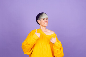 Stylish european woman on purple background approving doing positive gesture with hand, thumbs up smiling and happy for success