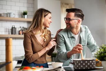 Happy smiling couple cooking together. Boyfriend and girlfriend preparing delicious food..