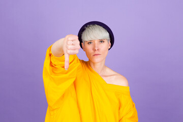 Stylish european woman on purple background looking unhappy and angry showing rejection and negative with thumbs down gesture. Bad expression.