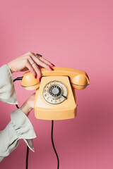 Cropped view of woman holding retro phone isolated on pink