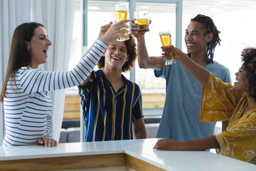 Diverse group of male and female colleagues raising glasses of beer at bar