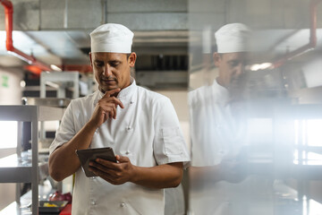 Portrait of mixed race male professional chefs looking at tablet
