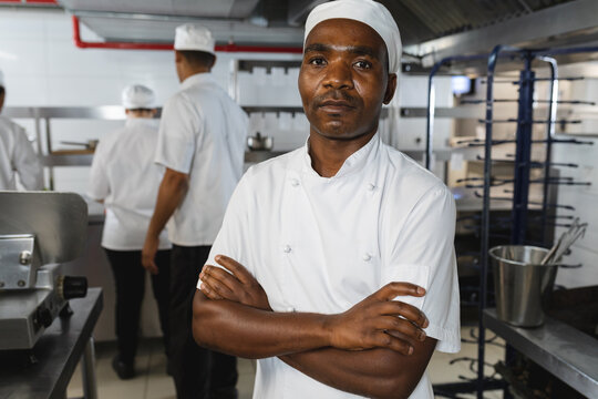 Portrait of african american male professional chef with colleagues in background