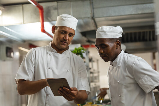 Portrait of diverse race male professional chefs discussig over tablet