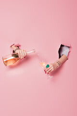 Cropped view of woman pouring champagne near pink background with holes © LIGHTFIELD STUDIOS