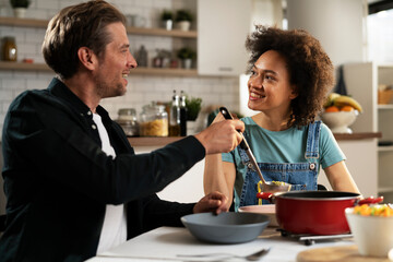 Boyfriend and girlfriend eating lunch together at home. Husband and wife enjoying in delicious food..
