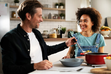 Boyfriend and girlfriend eating lunch together at home. Husband and wife enjoying in delicious food..