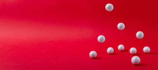 Closeup of white small falling balls on the red background.Empty space