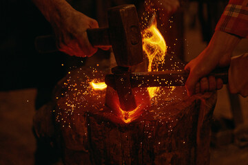 Blacksmiths hit molten metal with hammers close up