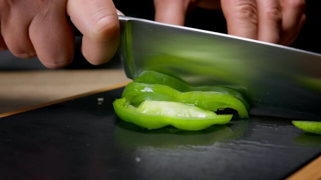 Female hands cutting in slices green bell pepper. Macro, 150 fps, slow motion. 