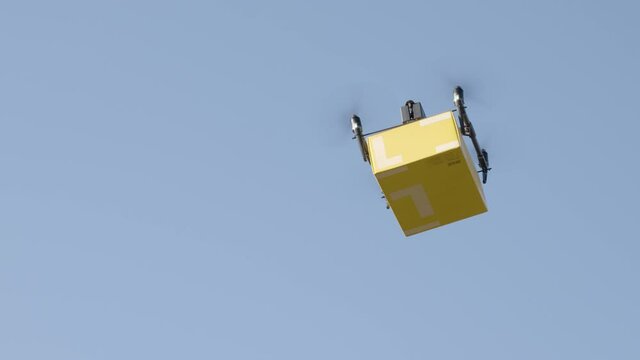 delivery drone carrying parcel flying across the blue sky