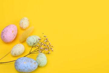 Easter eggs, a sprig of gypsophila, a lagurus on a yellow background. copy space