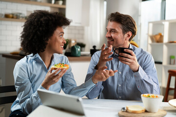 Loving couple drinking coffee and eating sandwich. Happy smiling wife enjoy in the morning with her husband..