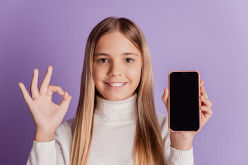 Photo of cheerful girl hold cellphone show okey sign