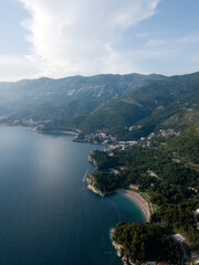 Aerial view of mountainous landscape Adriatic sea coast near Sveti Stefan island. Milocer beach, green sidehill with rich vegetation, trees, forest, coastal small villages, cities. Montenegro nature