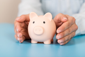 Piggy bank in hand on blue background, space for text. Finance, saving money. Business to success and saving for retirement concept