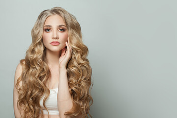 Perfect blonde woman with long healthy blonde curly hairstyle on white background