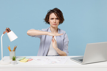 Young strict employee business woman 20s wear casual shirt sit work at white office desk with pc laptop holding stop gesture hands perpendicularly isolated on pastel blue background studio portrait.
