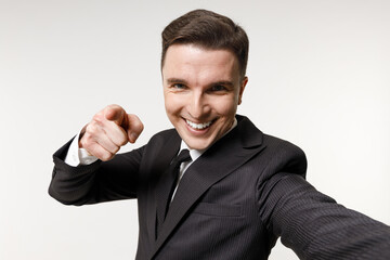Close up young employee business corporate lawyer man in classic formal black grey suit shirt tie work in office do selfie shot mobile phone point finger camera isolated on white background studio