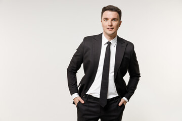 Fototapeta premium Young confident successful employee business corporate lawyer man 20s in classic formal black grey suit shirt tie work in office keeping hands in pockets isolated on white background studio portrait