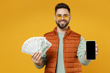 Young rich successful man in orange vest mint sweatshirt glasses holding mobile cell phone with...