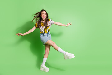 Fototapeta na wymiar Full length photo of happy cheerful young positive woman dance raise hands isolated on green color background