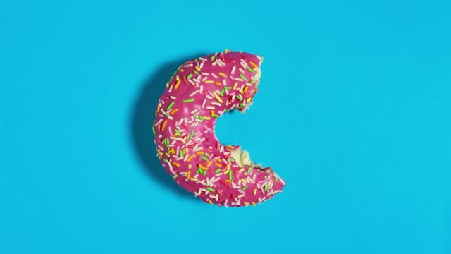 Creative food diet concept footage movie stop motion video donut bite on blue background.