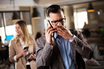 Young man in the office. Worried businessman talking to the phone