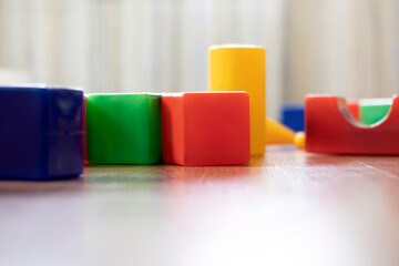 Colorful large cubes are randomly scattered on the floor in the children's playroom.