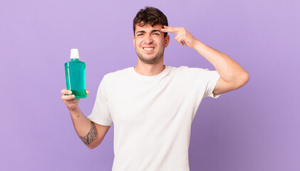 man with mouthwash feeling confused and puzzled, showing you are insane, crazy or out of your mind