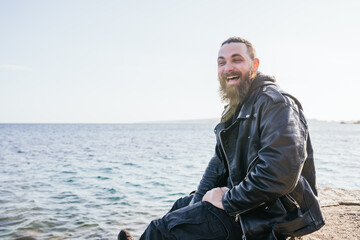 Caucasian man with long hair and beard laughing loudly by the sea at sunset on a beach in Portals. Palma de Mallorca, Spain (Copyspace)