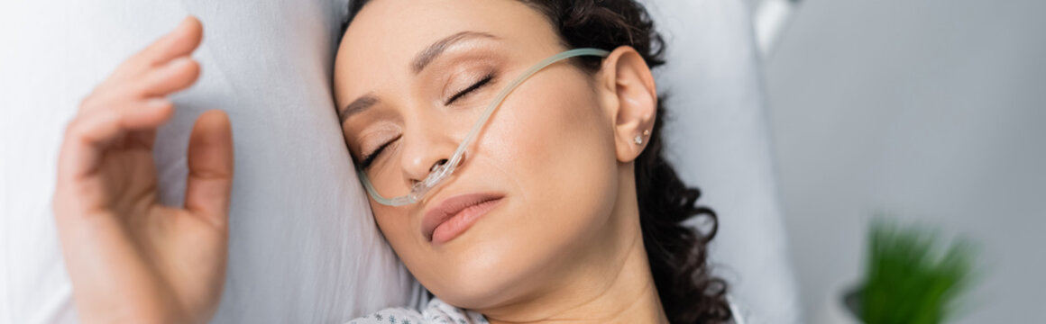 overhead view of ill african american woman with nasal cannula sleeping in hospital bed, banner